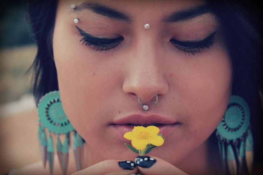 Creative close-up portrait with turquoise jewelry and a yellow flower